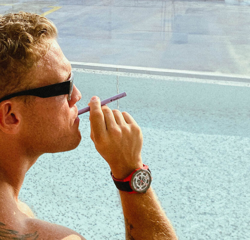 Person vaping disposable pen relaxing at home